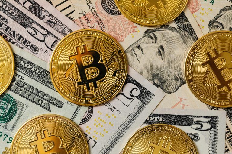 Golden bitcoins on a background of US dollar bills representing cryptocurrency and traditional money.