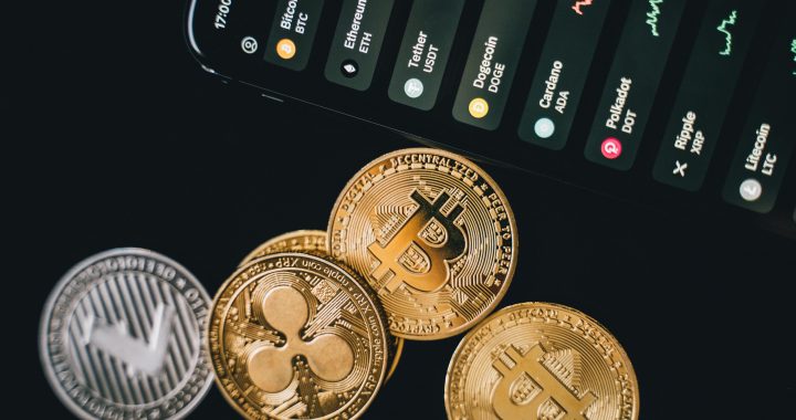 Close-up view of various cryptocurrency coins with a digital market display in the background.