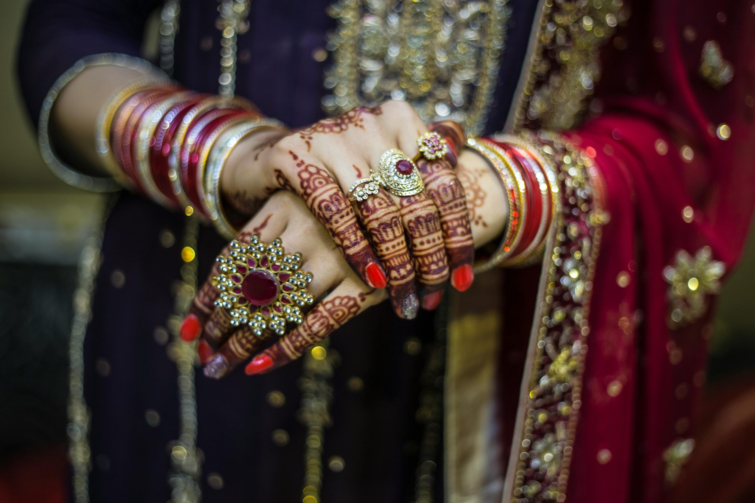 Detailed view of henna adorned hands with jewelry at a traditional Pakistani wedding in Lahore.